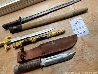 Group of three blades and their sheaths displayed on wooden surface