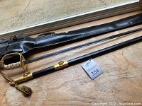 Full view of sword, scabbard and leather case arranged on wood surface