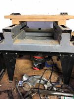 Front view of motorized jointer on wooden surface with battery and hand tools