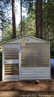 Front view of the outdoor metal shed with a door and vent on the roof peak.