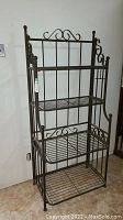 Front view of metal shelf organizer showing three wire shelves and decorative top scrollwork.