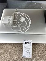 Closed silver MacBook Air laptops stacked with a MagSafe 2 adapter on top