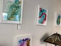 Four framed abstract fluid art pieces hanging on a wall