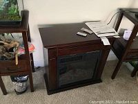 Full view of the wood-framed electric fireplace with dark wood finish and realistic flame effect visible inside.