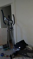 Photo showing full elliptical machine with upright handles, digital display, and knee covers and glove on machine.