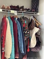 Closet rack with hanging women's jackets and sweaters size small to medium in various colors and patterns. Above on the shelf are multiple pairs of women's shoes size 7 and bags, including a black backpack with pink dog print.