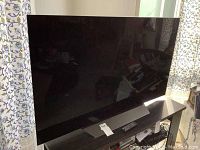 Front view of LG 55-inch OLED TV on stand with remote control placed in front