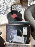 Reproduction phonograph record player on white ottoman with stack of vinyl records in front