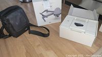 DJI Mavic Pro retail box, black DJI carrying bag and open charger hub packaging on wooden floor
