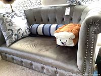 Gray velvet miniature loveseat with three pillows including decorative square, striped bolster, and novelty bread-shaped pillow