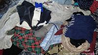 Pile of assorted sleepwear and robes in various colors including plaid and solid patterns.
