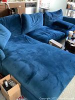 Blue velvet sectional sofa with cushions, chaise lounge section, and surrounding room context.