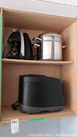 Shelf with black and white Toastess espresso/cappuccino maker, stainless steel steamer pot, black Hamilton Beach bread machine.