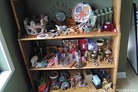 Shelf with multiple decorative items including candle holders, coasters, small plates, crosses, back scratcher, and jar