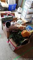 Boxes filled with assorted Christmas decorations including an artificial Christmas tree, ornaments, and holiday textiles.