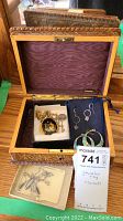 Jewelry box opened revealing multiple jewelry pieces inside as well as a key and a label showing lot info