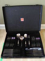 Open view of flatware set arranged in black case showing cutlery types.