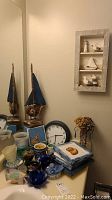 View of wooden boat models, wall clock, Moorcroft bowl, decorative containers, candle holders on a shelf near mirror.