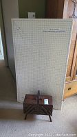 Photo showing wooden sewing kit box in front of a large sewing mat with grid layout, both in a carpeted room.