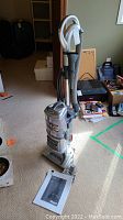 Full view of Shark upright vacuum cleaner with handle and hose attachment in room setting