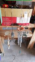 Full view of three hanging decorative wind chimes on wooden shelf