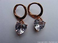 Pair of rose gold hoop earrings each set with a 1.3 ct heart-shaped clear simulated diamond, showing top and front view.