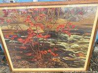 Close up image focusing on the branches and red maple leaves, showing the flowing river background and rocks beneath, highlighting details of the print.