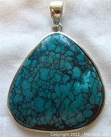 Front view of the turquoise pendant showing vibrant blue stone with black matrix set in silver.