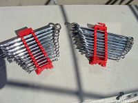 Two sets of combination wrenches in red plastic holders on a flat surface with shadows