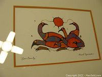 Front view of framed lithograph showing stylized loons and red sun, signed 'Norval Morrisseau' with double-tone mat and black frame.