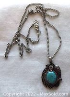 Photo of turquoise and sterling silver Navajo pendant with chain laid out on white fabric