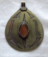Front of tear-shaped silver pendant showing bezel-set amber and pressed line designs.