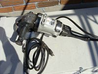 Left side view of the Black & Decker angle grinder, showing handle, power cord and grinder head with guard.