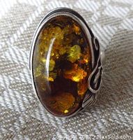 Front view showing large oval amber stone with golden inclusions and silver bezel.