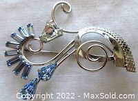 Front photo showing detailed design and arrangement of blue and clear rhinestones on silver brooch