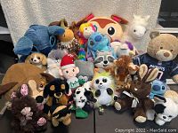 Wide view of the collection of 22 plush stuffed animals including teddy bears, dogs, raccoon, llama, Stitch, bunny and others