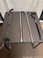 Four walking canes arranged on a black table - two silver adjustable canes, one black forearm support cane, and one quad base cane