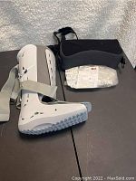 Side view of new Aircast FP Walker medium orthopedic walking boot with carrying case on a black surface.