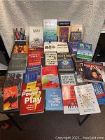 Full view of 24 books arranged on surface showing varied titles, topics, and cover art.