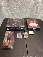 Full view of all items in the lot showing the Monopoly board game, Jon Snow figure, and three card decks.