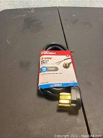 Photo showing the Hyper Tough branded 4-wire dryer cord in its original packaging, black cable with brass 4-prong plug, labeled for 10 ampere dryer use, length 6 feet.