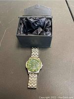 Jerome Lemars men's wristwatch with green dial resting on or near its original box showing satin interior.