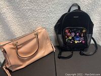 Photo of two bags side by side: a nude handbag and a black backpack with floral decorations on front pocket.