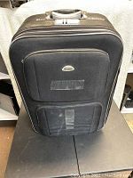 Front view of black Simpson travel bag showing main body and two zippered front compartments.