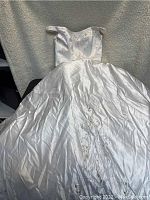Full view of the white wedding dress laid flat showing full skirt and bodice detail.