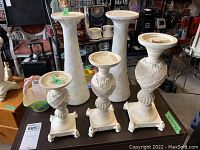 Set of three white ceramic candleholders on a wooden table in a garage, showing heights and details.