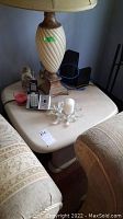Photo of one of the two matching heavy square end tables with various items on top including a lamp, remote control, candle, and other small objects (which are not included). Photo shows table surface and adjacent furniture.