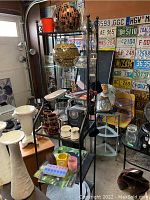 Wide view of black shelving unit with espresso set cups and saucers, vases, decorative orb, glass pitcher, figurines, and miscellaneous items.