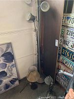 Three lamps arranged closely near wall and door, showing full vertical view of floor lamp with three adjustable metal lights, smaller table and desk lamps on floor.