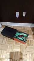 Nike LeBron X green basketball shoes in original box on wooden floor near brown wall.